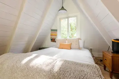 a bedroom with a white bed in a attic at Modern A-Frame Cabin with Loft, Firepit and Grill in Catskill