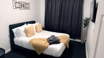 a bedroom with a bed with white sheets and pillows at Nona - Cozy 3BR Apt with Parking, Desk & Fast WiFi near Yale, Quinnipiac, SCSU & Hospitals in Hamden