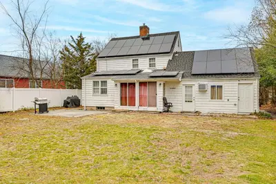 a white house with a solar roof on a yard at 1 Mi to Connecticut River Home with Large Backyard in Glastonbury