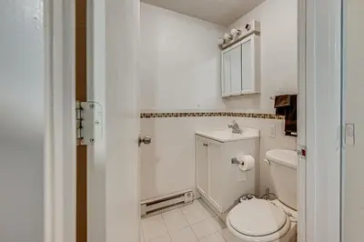 a white bathroom with a toilet and a sink at 1 Mi to Connecticut River Home with Large Backyard in Glastonbury