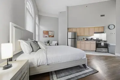 a white bedroom with a bed and a kitchen at Relaxing studio perfect for extended visits in New Haven