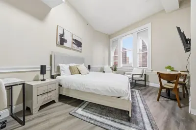 a white bedroom with a bed and a desk at Homey studio perfect for long-term guests in New Haven