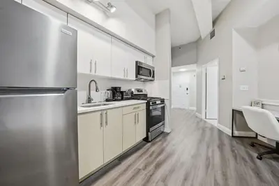 a kitchen with white cabinets and a stainless steel refrigerator at Homey studio perfect for long-term guests in New Haven