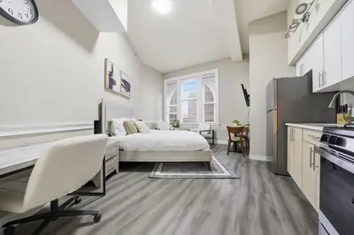 a bedroom with a bed and a desk and a kitchen at Homey studio perfect for long-term guests in New Haven