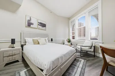 a white bedroom with a bed and a desk at Homey studio perfect for long-term guests in New Haven