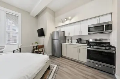 a bedroom with a bed and a kitchen with a stove at Homey studio perfect for long-term guests in New Haven