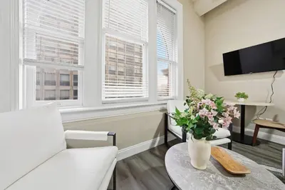 a living room with a white couch and a table with flowers at Homey studio perfect for long-term guests in New Haven