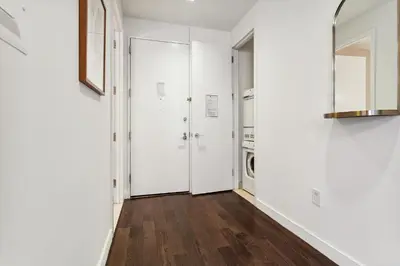 a hallway with white walls and wood floors and a door at FiDi Studio w Work Setup by Anyplace - 10250 in New York