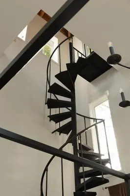 a spiral staircase in a room with a window at Secluded escape with hot tub, pizza oven, fireplace in Taghkanic