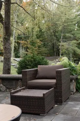 a brown wicker chair sitting on a patio at Secluded escape with hot tub, pizza oven, fireplace in Taghkanic