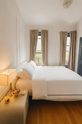 a bedroom with a large white bed and a window at Elegant Upper East Side Studio Retreat Near Central Park and The Met in New York