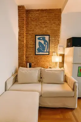 a living room with a couch and a brick wall at Elegant Upper East Side Studio Retreat Near Central Park and The Met in New York