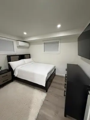 a bedroom with a white bed and a black cabinet at Pelham parkway North in Baychester