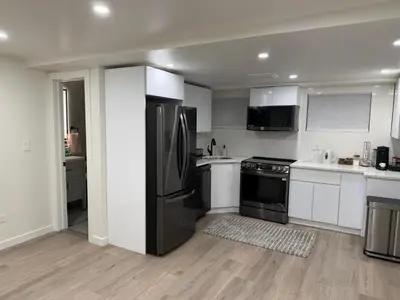 a kitchen with stainless steel appliances and white cabinets at Pelham parkway North in Baychester