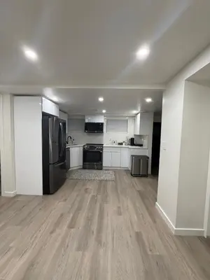 a large kitchen with white cabinets and stainless steel appliances at Pelham parkway North in Baychester