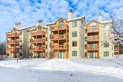 a large apartment building with snow in front of it at Walk to Mt Snow Ski Shuttle! Condo with Resort Perks in West Dover