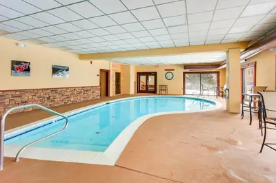 a pool in a hotel room with chairs and a table at Walk to Mt Snow Ski Shuttle! Condo with Resort Perks in West Dover