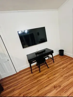 a black table and chair in a room with a flat screen tv at Big Mama's House in Paterson