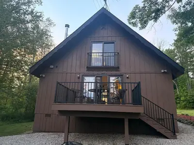 a house with a gambrel roof and a balcony at Little Longbow Lakefront Chalet in Becket