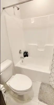 a white bathroom with a toilet and a bath tub at Luxury Townhouse Near West Point in Highland Falls