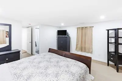 a bedroom with a bed and a dresser and a television at Orange NJ 2BR Duplex | Walk to Train + 2BA in Orange