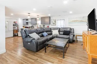 a living room with a leather couch and a kitchen at Orange NJ 2BR Duplex | Walk to Train + 2BA in Orange