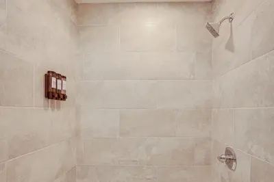 a bathroom with a shower with beige tiles at Home with Lake Views and Deck in New Jersey Highlands! in Stanhope