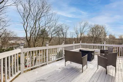 a porch with two chairs and a table on a fence at Home with Lake Views and Deck in New Jersey Highlands! in Stanhope
