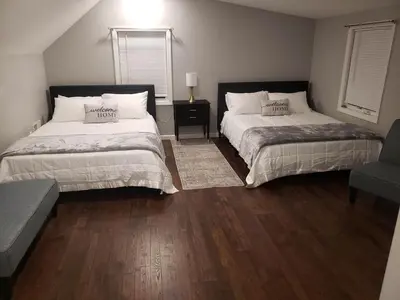 two beds in a room with wood floors at Attractive and Cozy Apartment - 4 bdrms 2 bths in Paterson