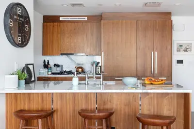 a kitchen with wooden cabinets and a counter with bar stools at Stylish Williamsburg One Bedroom Condo Near Manhattan in Brooklyn