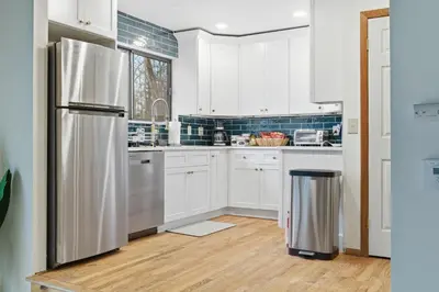 a kitchen with white cabinets and a stainless steel refrigerator at Monster-themed lake front cabin with firepit sauna hot tub game room in Tobyhanna