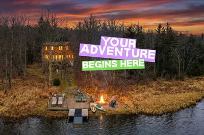 a sign that reads your adventure begins here with a campfire at Monster-themed lake front cabin with firepit sauna hot tub game room in Tobyhanna
