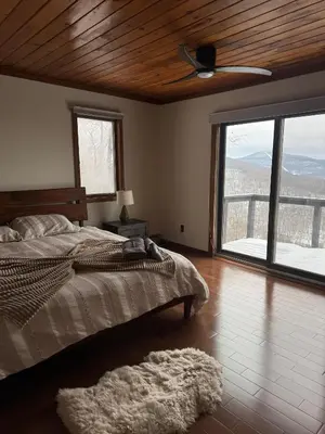 a bedroom with a bed and a large window at Serene 4-bedroom chalet in charming Catskills awaits you- amazing Mountain Views in Bovina Center