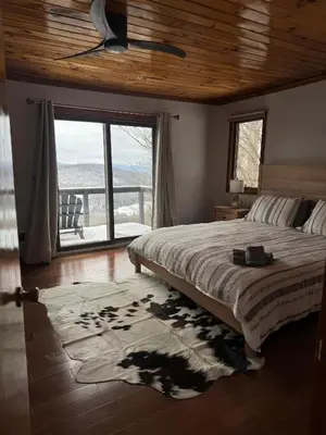 a bedroom with a bed and a large window at Serene 4-bedroom chalet in charming Catskills awaits you- amazing Mountain Views in Bovina Center
