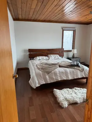 a bedroom with a large bed with a wooden ceiling at Serene 4-bedroom chalet in charming Catskills awaits you- amazing Mountain Views in Bovina Center