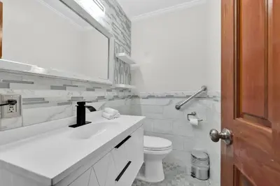 a white bathroom with a sink and a toilet at Big Bass Hideaway with Hot Tub in Gouldsboro