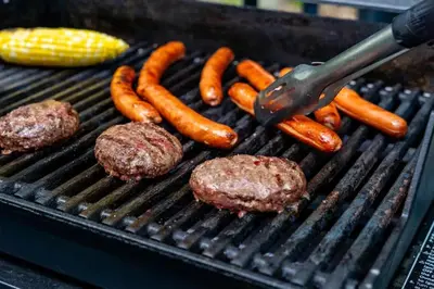three hamburgers and carrots on a grill with a spatula at 4BDRM Games Family Frndly Fire Pit Masthope in Lackawaxen