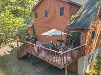 an outdoor deck with a table and an umbrella at Charming Getaway Minutes from Lake Wallenpaupack in Tafton