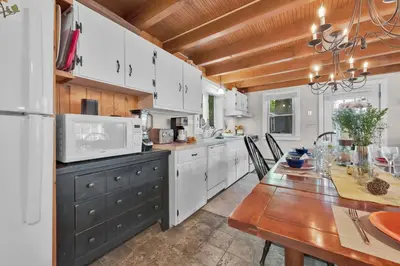 a kitchen with white cabinets and a wooden table at Lake Wallenpaupack Lakefront Private Boat Slip in Greentown