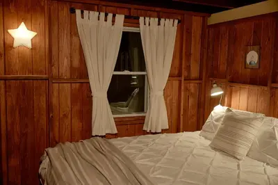 a bedroom with a bed and a window with curtains at Woodside Cabin in Delaware Water Gap in Dingmans Ferry