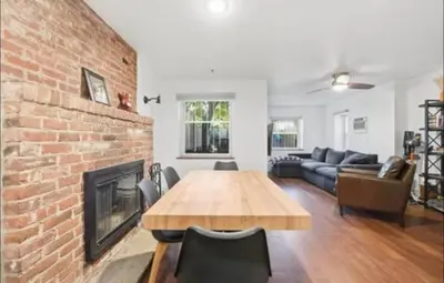 a living room with a brick fireplace and a wooden table at New Cozy Must Have Stay! 10 minutes to NYC in Hoboken