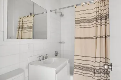 a white bathroom with a sink and a shower curtain at Midtown 1BR w Gym Doorman nr Grand Central NYC-746 in New York