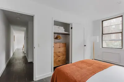 a bedroom with white walls and a bed with an orange blanket at Blueground Dumbo rooftop wd nr bridge NYC-1668 in Brooklyn