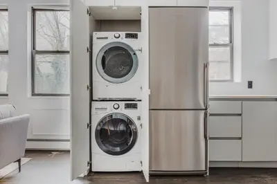 a washer and dryer in a kitchen next to a refrigerator at Blueground Dumbo rooftop wd nr bridge NYC-1668 in Brooklyn
