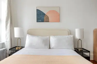 a bedroom with a bed with two lamps on tables at Blueground Alphabet City washer nr Tompkins Square Park NYC-2161 in New York