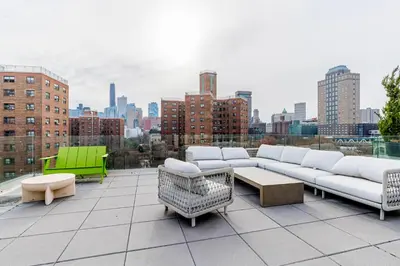 a rooftop patio with couches and tables and a city skyline at Blueground Downtown Brooklyn rooftop nr Brooklyn Bridge NYC-2186 in Brooklyn