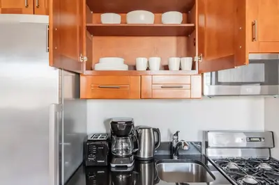 a kitchen with wooden cabinets and a counter top at Blueground Nolita view nr Washington Square NYC-2051 in New York