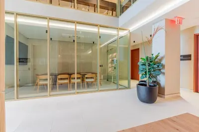a dining room with glass walls and a potted plant at Blueground Greenpoint rooftop nr Transmitter Park NYC-2196 in Brooklyn