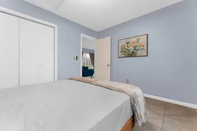 a white bedroom with a bed and a painting on the wall at Willow Haven 2BR Cozy Retreat, Close to Hartford in Manchester