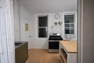 a kitchen with a stove and a sink and two windows at Cozy Little Italy Retreat Steps from SoHo in New York